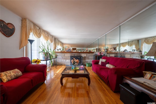 living room with hardwood / wood-style floors, a stone fireplace, and crown molding