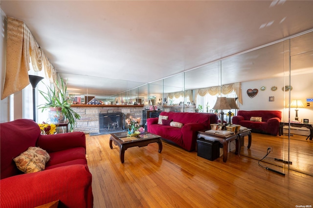 living room with hardwood / wood-style floors, a stone fireplace, and a baseboard radiator