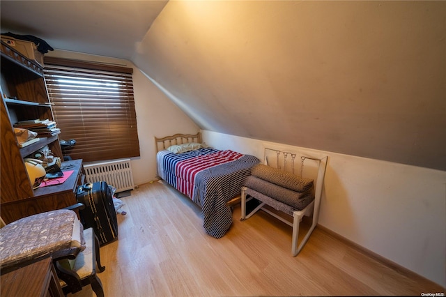 bedroom with light hardwood / wood-style floors, lofted ceiling, and radiator