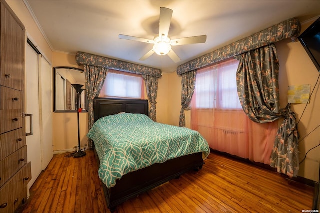 bedroom with ceiling fan, a closet, wood-type flooring, and ornamental molding