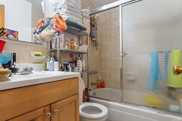 full bathroom featuring bath / shower combo with glass door, backsplash, toilet, and vanity