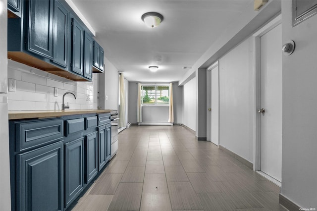 kitchen with blue cabinets, wood counters, tasteful backsplash, and sink