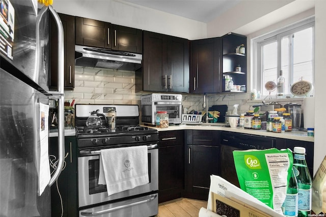 kitchen featuring stainless steel gas stove, decorative backsplash, refrigerator, and light wood-type flooring