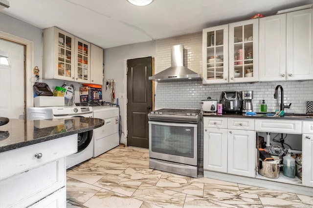 kitchen featuring washing machine and dryer, stainless steel range, white cabinets, and wall chimney range hood