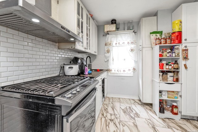 kitchen featuring gas stove, sink, wall chimney range hood, tasteful backsplash, and white cabinets