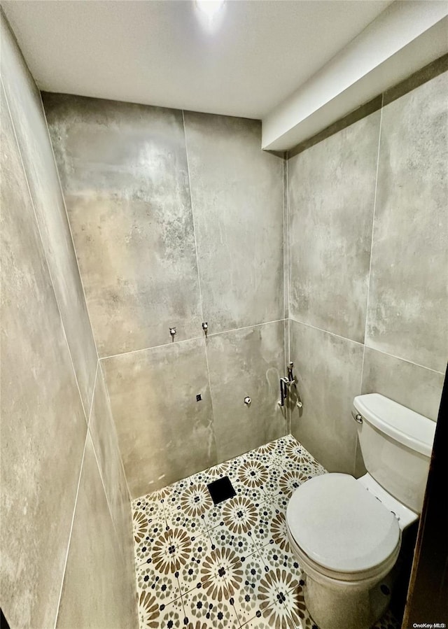 bathroom featuring toilet, tile walls, and walk in shower