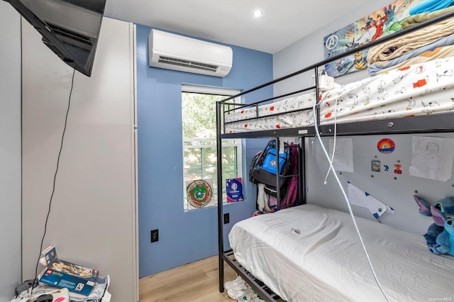 bedroom featuring light hardwood / wood-style floors and a wall unit AC