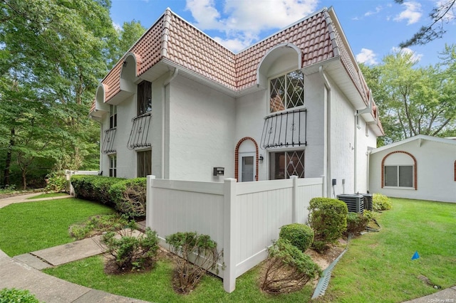 view of property exterior featuring central AC and a lawn