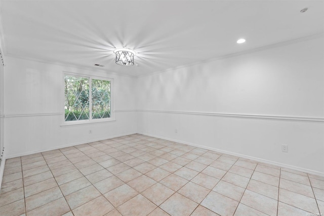 tiled spare room featuring a notable chandelier and ornamental molding