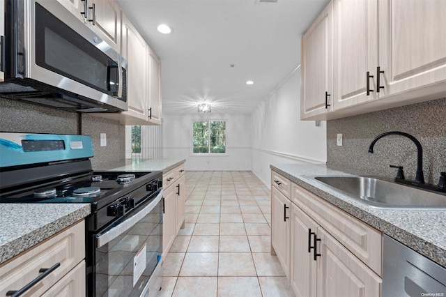 kitchen with appliances with stainless steel finishes, backsplash, light tile patterned floors, and sink