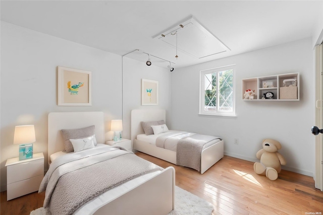 bedroom with wood-type flooring and track lighting