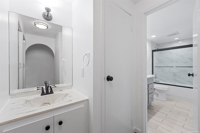 full bathroom featuring vanity, toilet, and combined bath / shower with glass door