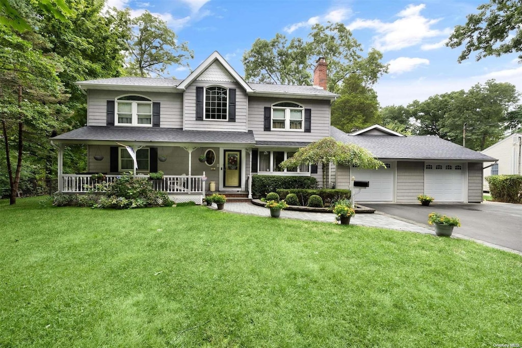 view of front of property featuring a front lawn, covered porch, and a garage