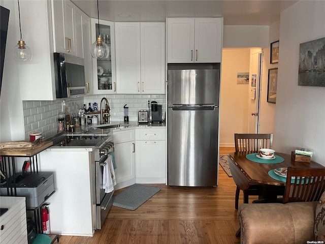 kitchen with dark hardwood / wood-style flooring, stainless steel appliances, sink, decorative light fixtures, and white cabinets