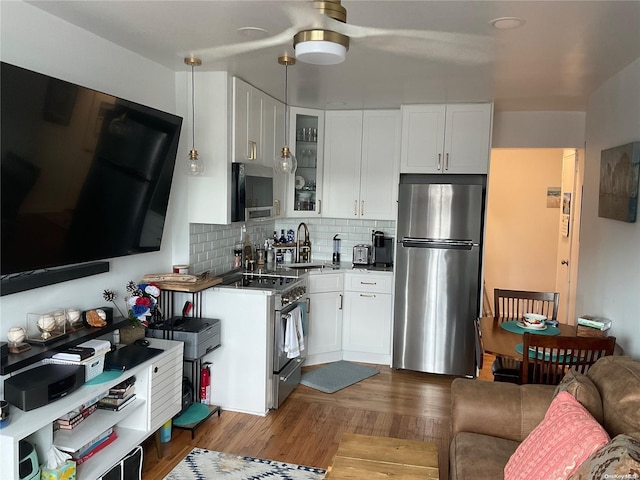 kitchen featuring appliances with stainless steel finishes, sink, decorative light fixtures, white cabinets, and dark hardwood / wood-style floors