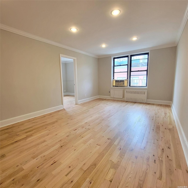 empty room featuring radiator, cooling unit, light hardwood / wood-style floors, and ornamental molding