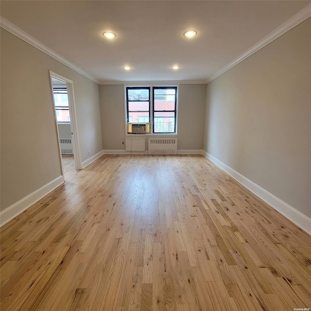 spare room with radiator, crown molding, plenty of natural light, and light hardwood / wood-style floors