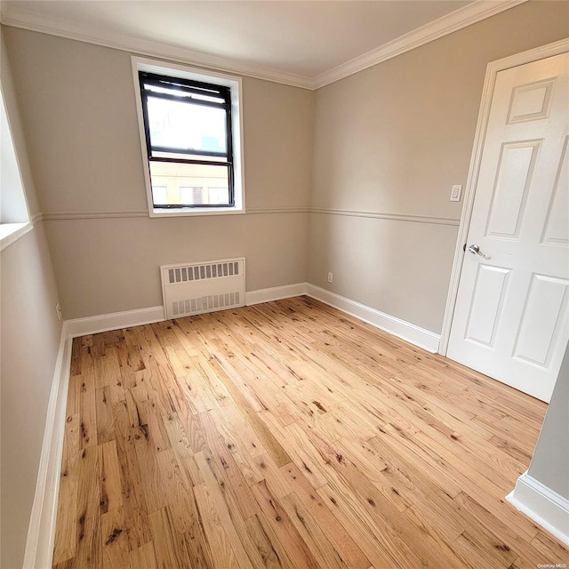 empty room featuring radiator heating unit, light hardwood / wood-style floors, and crown molding