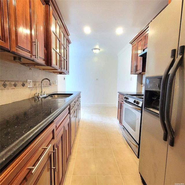 kitchen featuring tasteful backsplash, dark stone counters, stainless steel appliances, sink, and light tile patterned floors