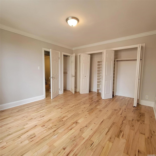 unfurnished bedroom featuring two closets, light hardwood / wood-style flooring, and crown molding