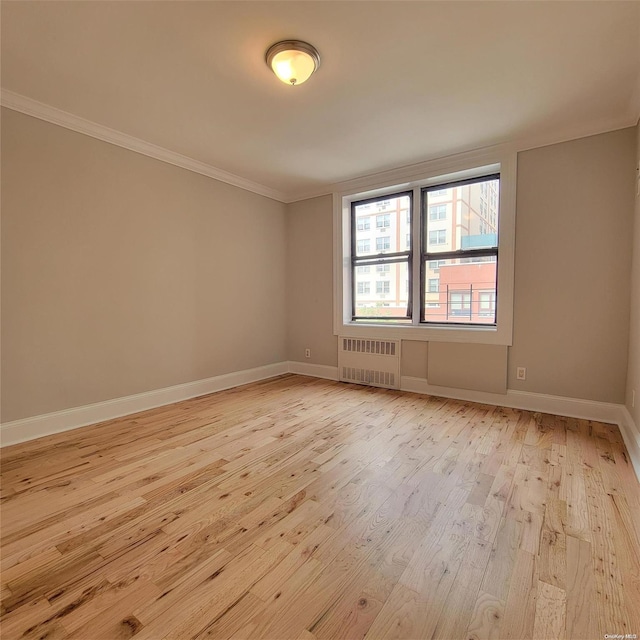 unfurnished room featuring light wood-type flooring, crown molding, and radiator