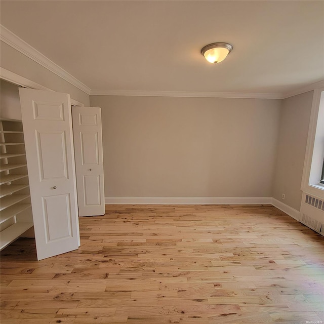 spare room featuring light wood-type flooring, crown molding, and radiator