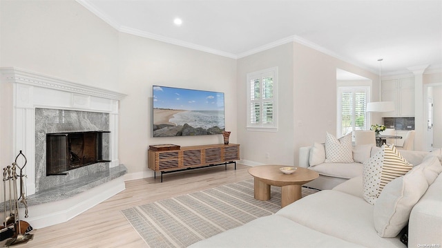 living room featuring ornamental molding, a high end fireplace, and light hardwood / wood-style flooring