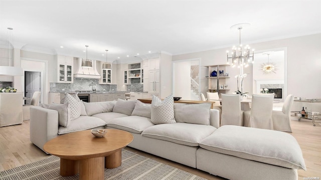 living room featuring crown molding, a chandelier, and light wood-type flooring