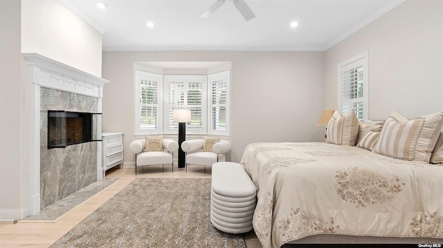 bedroom with a high end fireplace, light hardwood / wood-style floors, ceiling fan, and ornamental molding