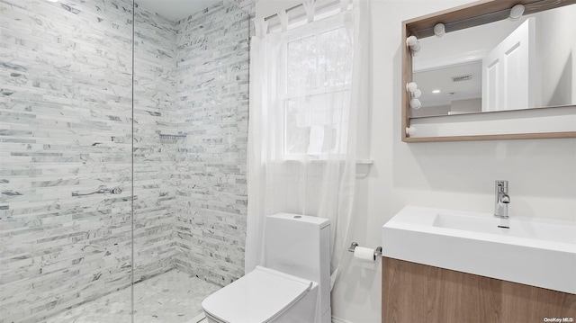 bathroom with vanity, toilet, and tiled shower