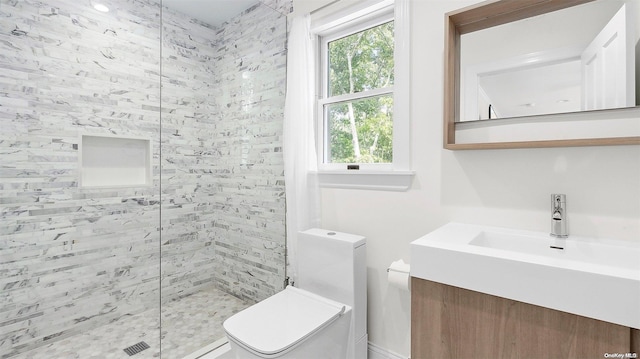 bathroom featuring tiled shower, vanity, and toilet