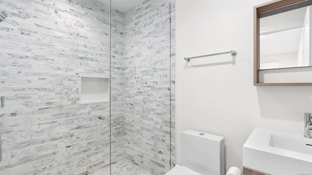 bathroom featuring vanity, toilet, and a tile shower