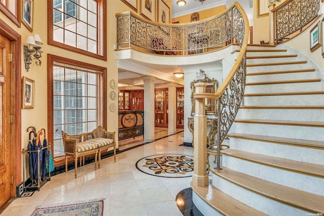 entrance foyer with ornamental molding, a high ceiling, and decorative columns