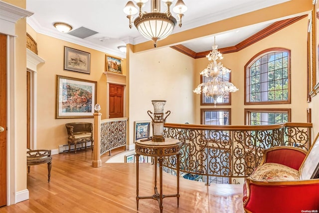 interior space with a notable chandelier, light hardwood / wood-style floors, baseboard heating, and crown molding