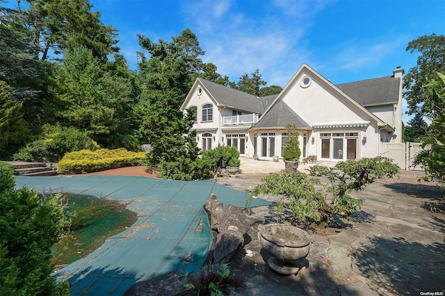 back of property with a patio area, french doors, and a covered pool