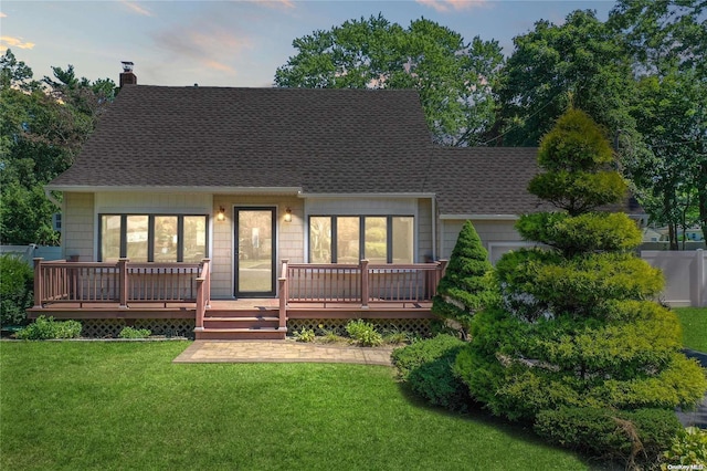 back house at dusk featuring a yard and a deck