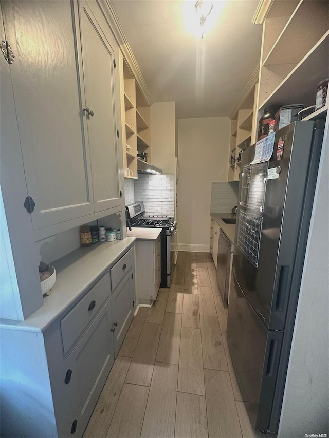 kitchen with backsplash, white cabinetry, stainless steel appliances, and light hardwood / wood-style flooring