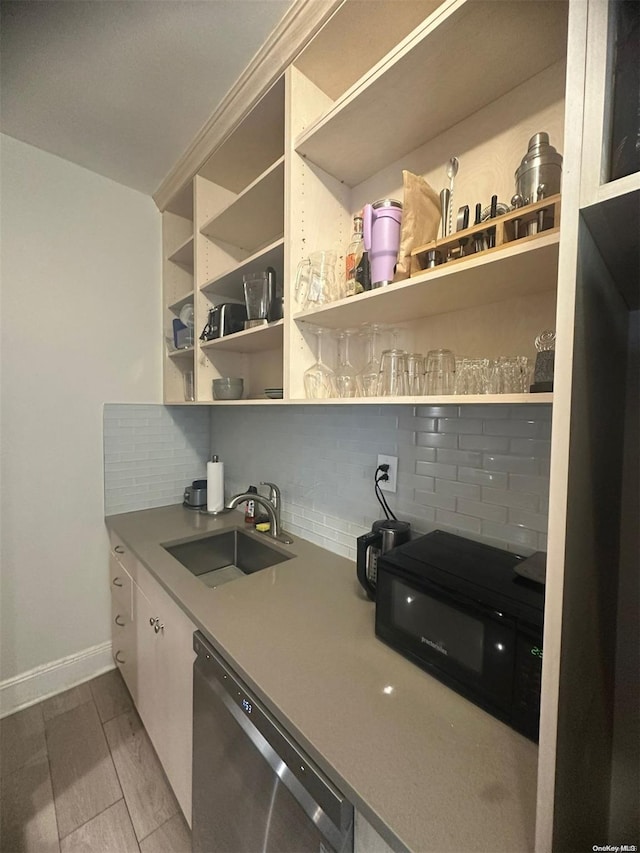 kitchen featuring backsplash, stainless steel dishwasher, ornamental molding, sink, and wood-type flooring