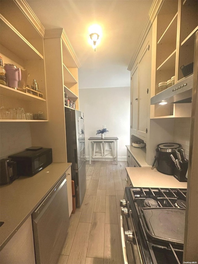 kitchen featuring white cabinets, light wood-type flooring, stainless steel appliances, and ornamental molding