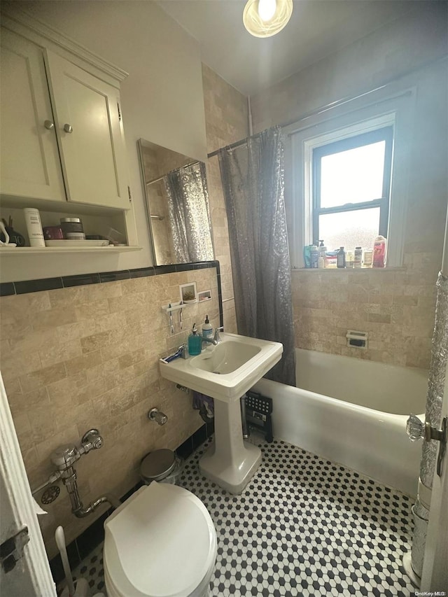 bathroom with tile patterned floors, toilet, shower / bathtub combination with curtain, and tile walls