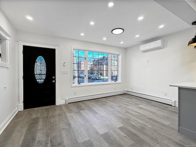 foyer with a wall mounted air conditioner, a baseboard heating unit, and light hardwood / wood-style flooring