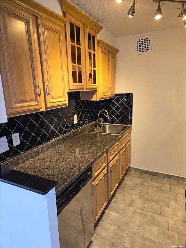 kitchen featuring stainless steel dishwasher, decorative backsplash, sink, and dark stone counters