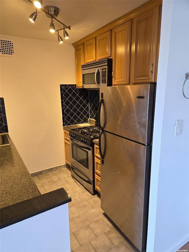 kitchen featuring decorative backsplash, a textured ceiling, and appliances with stainless steel finishes