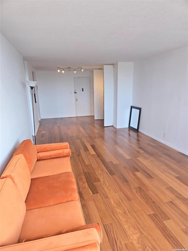 unfurnished living room featuring rail lighting, wood-type flooring, and a textured ceiling