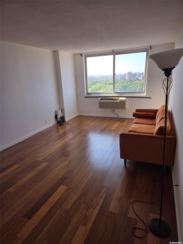 unfurnished living room with a textured ceiling, dark wood-type flooring, and a wall mounted air conditioner