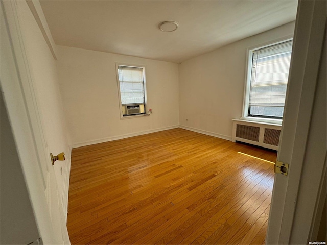 empty room with light wood-type flooring, radiator, and cooling unit