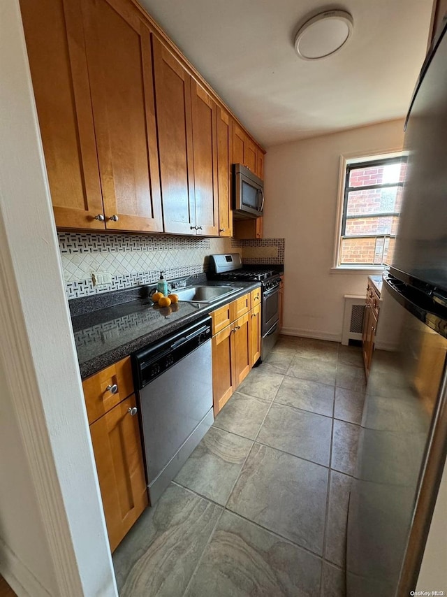 kitchen with appliances with stainless steel finishes, tasteful backsplash, radiator, and sink