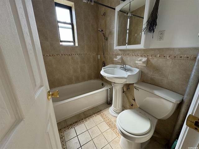 bathroom with tile patterned floors, tiled shower / bath, tile walls, and toilet