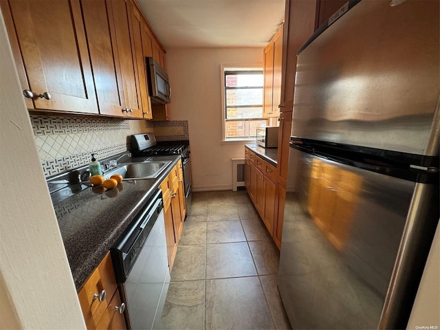 kitchen with light tile patterned flooring, sink, appliances with stainless steel finishes, and tasteful backsplash