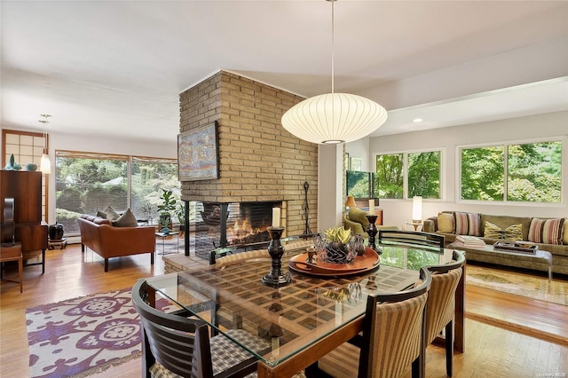 dining space featuring a brick fireplace, a healthy amount of sunlight, and light hardwood / wood-style flooring